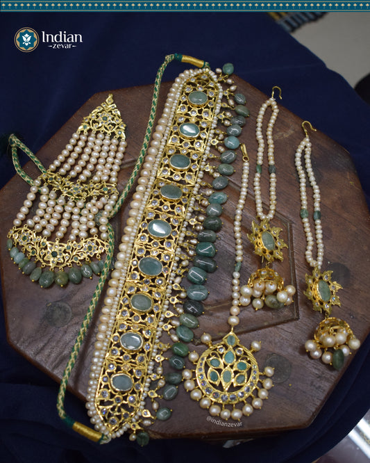 A close-up image of a Hyderabadi Jadau bridal choker set with real pearls, emeralds, and intricate Jadau work.