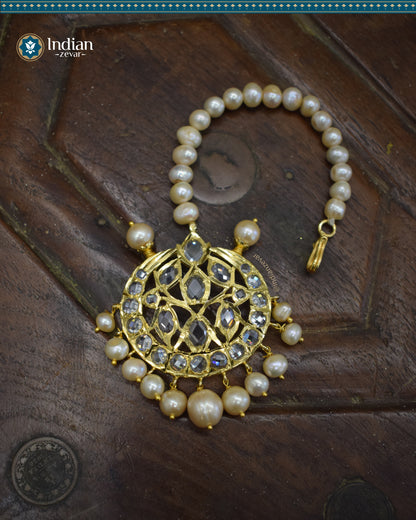 A close-up image of a Hyderabadi Jadau maang tika, adorned with CZ Polki stones, real freshwater pearls, and intricate gold-plated alloy work.