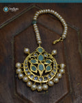 A close-up image of a Hyderabadi Jadau maang tika, adorned with emeralds, CZ Polki stones, and real freshwater pearls. The maang tika is handcrafted with gold-plated alloy and features intricate Jadau work.