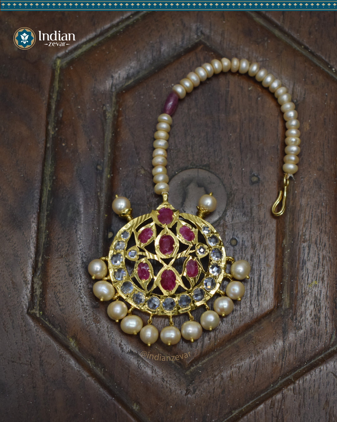 A close-up image of a Hyderabadi Jadau maang tika, adorned with rubies, CZ Polki stones, and real freshwater pearls. The maang tika is handcrafted with gold-plated alloy and features intricate Jadau work