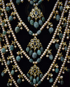 Closeup of Indian Zevar Grand Emerald Sathlada with seven strings of freshwater pearls, emerald Jadau hangings, CZ Polki and matching Angoor Goshe chandelier earrings.