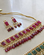 Jewelry set with red gemstones and gold accents on a light background. Handcrafted Indo-Western choker set with pearls, emerald accents & Jadau work – perfect Indian bridal jewelry and wedding choker design.