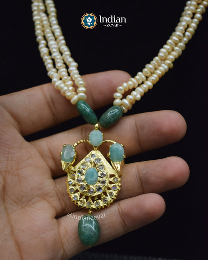 Traditional Indian gold-plated necklace set featuring Jadau work with pearls and green emerald stones.