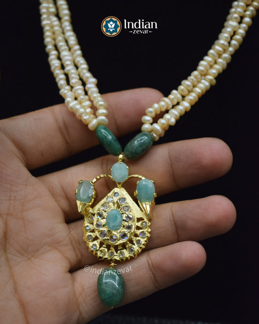 Traditional Indian gold-plated necklace set featuring Jadau work with pearls and green emerald stones.